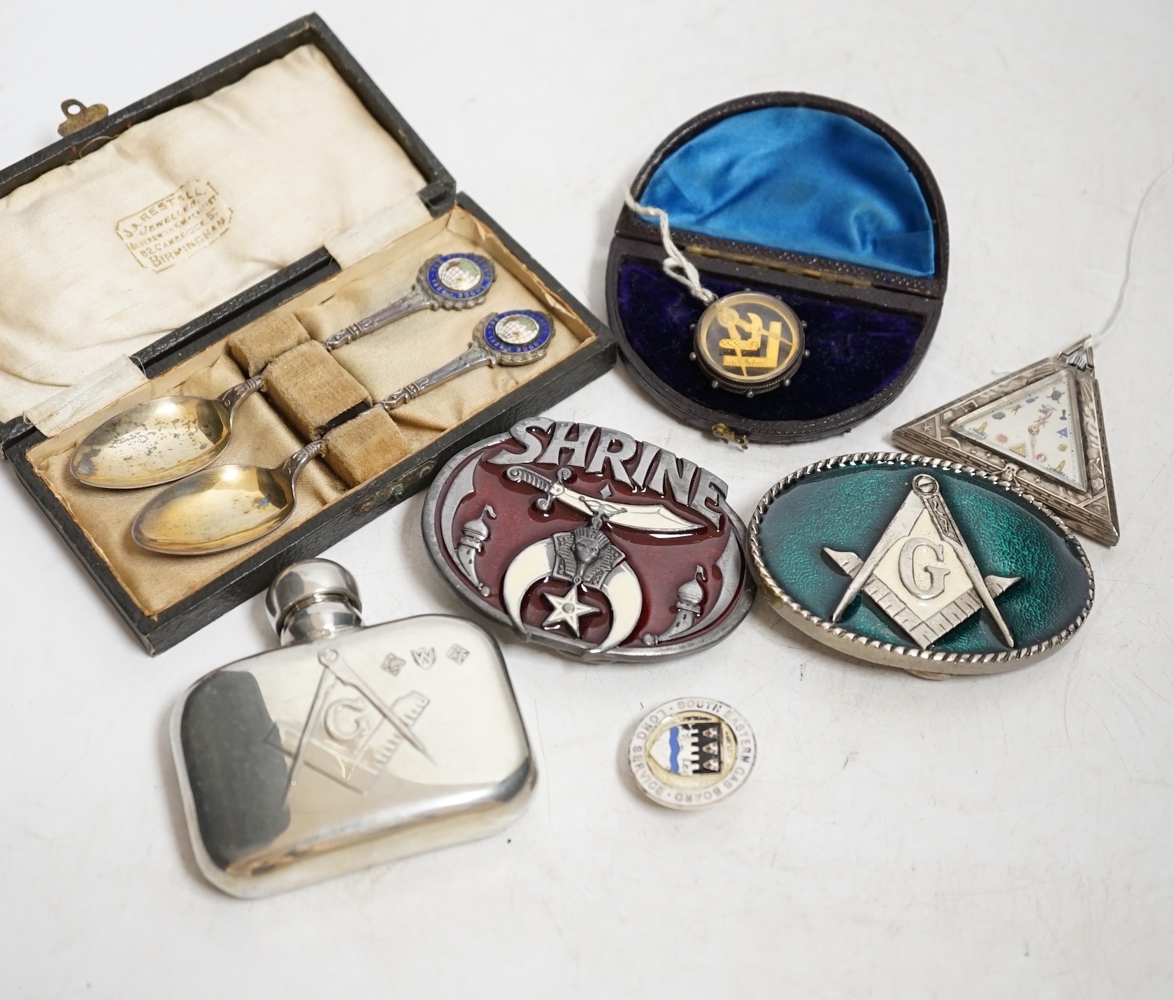A collection of objects to include a triangular Masonic silver pocket watch, assorted Masonic fobs, enamel buckles, silver presentation spoons and sundries. Condition - varies, mostly fair
